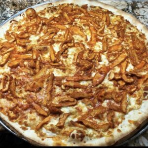 A Buffalo Chicken Pie with spicy buffalo chicken, fresh mozzarella, and a drizzle of creamy ranch dressing on a baked crust.
