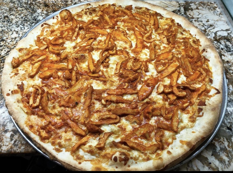 A Buffalo Chicken Pie with spicy buffalo chicken, fresh mozzarella, and a drizzle of creamy ranch dressing on a baked crust.