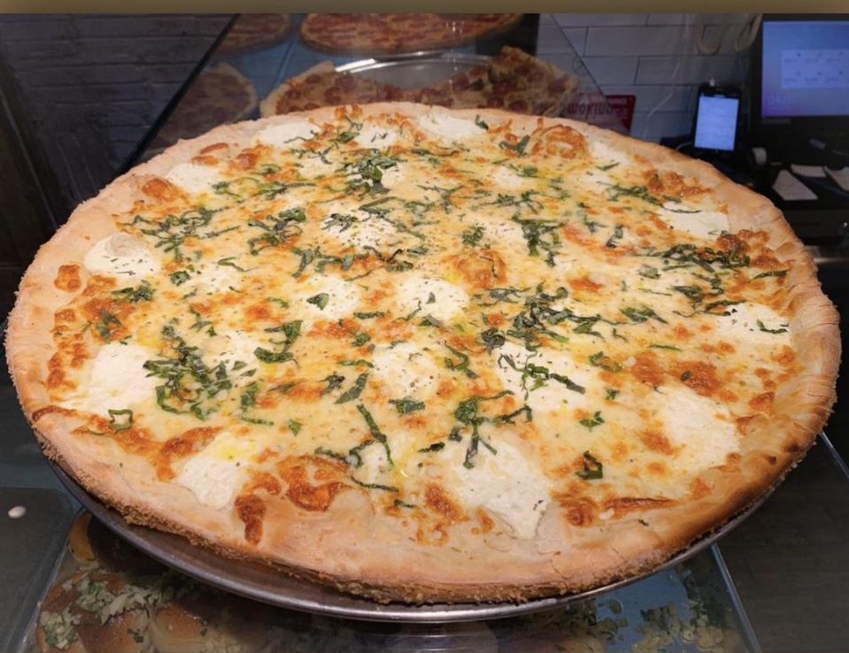 A Formaggio Bianco white pizza topped with fresh ricotta cheese, aged mozzarella, Parmigiano Reggiano, basil, and a drizzle of olive oil.