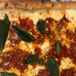 A Grandma Rosemarie Pie with a thin and crispy crust, topped with fresh tomatoes, garlic, basil, mozzarella, and a hint of olive oil.