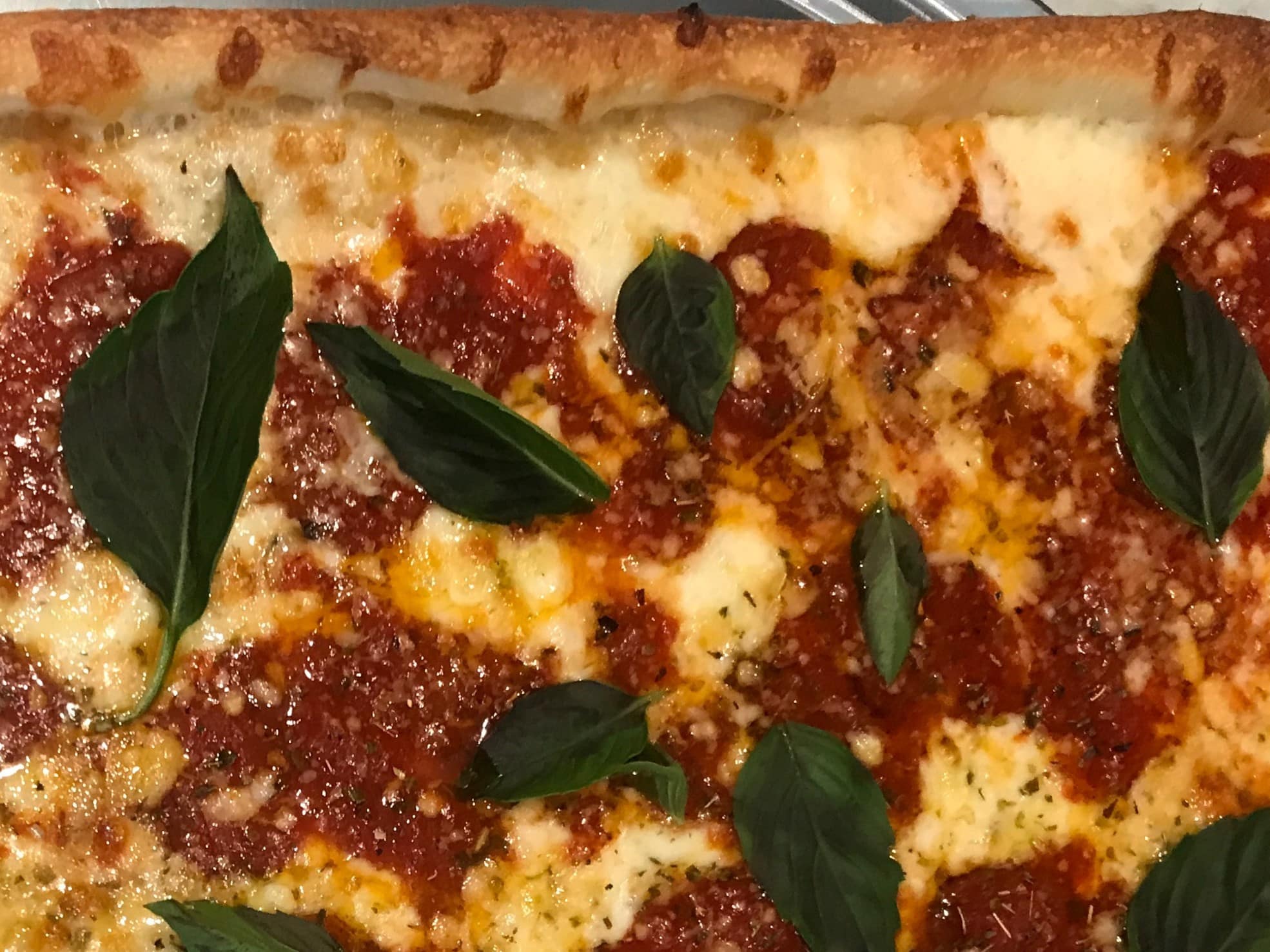 A Grandma Rosemarie Pie with a thin and crispy crust, topped with fresh tomatoes, garlic, basil, mozzarella, and a hint of olive oil.