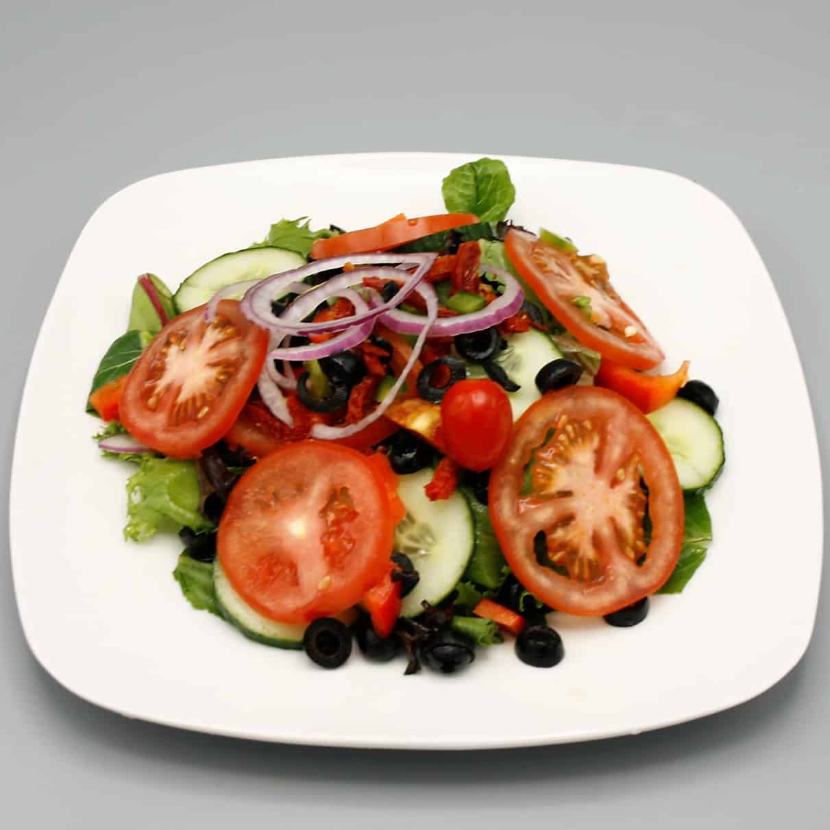 House salad with romaine lettuce, mixed greens, vine tomatoes, Bermuda onions, cucumbers, black olives, and peppers.