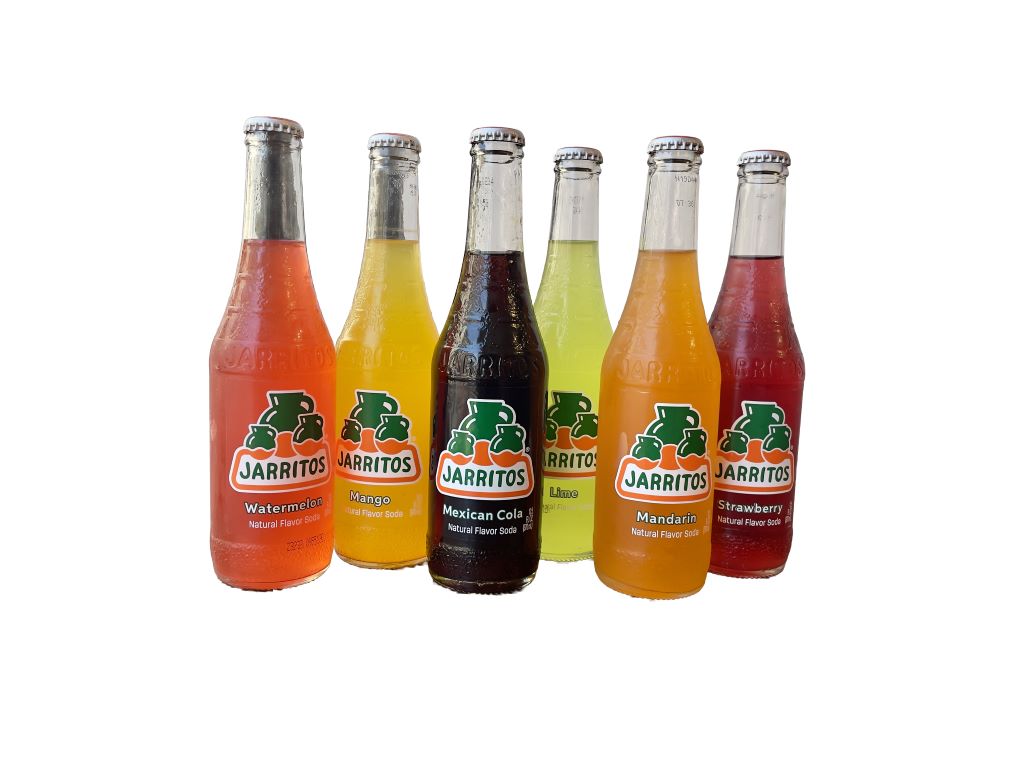 A variety of Jarritos soda bottles are arranged on a table.
