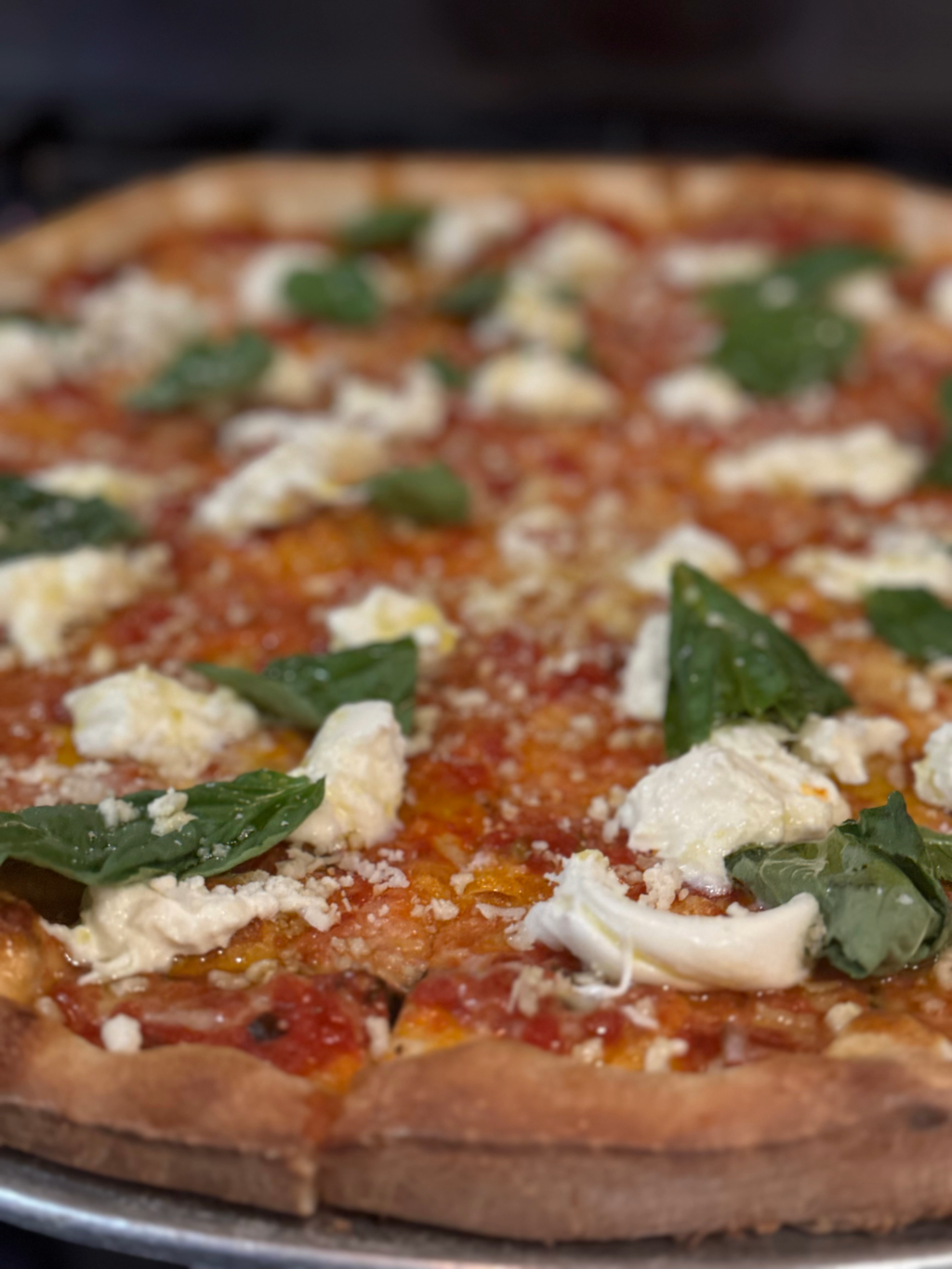 Burrata pizza with creamy imported burrata cheese, San Marzano marinara sauce, fresh basil, Parmigiano Reggiano, and a drizzle of olive oil.
